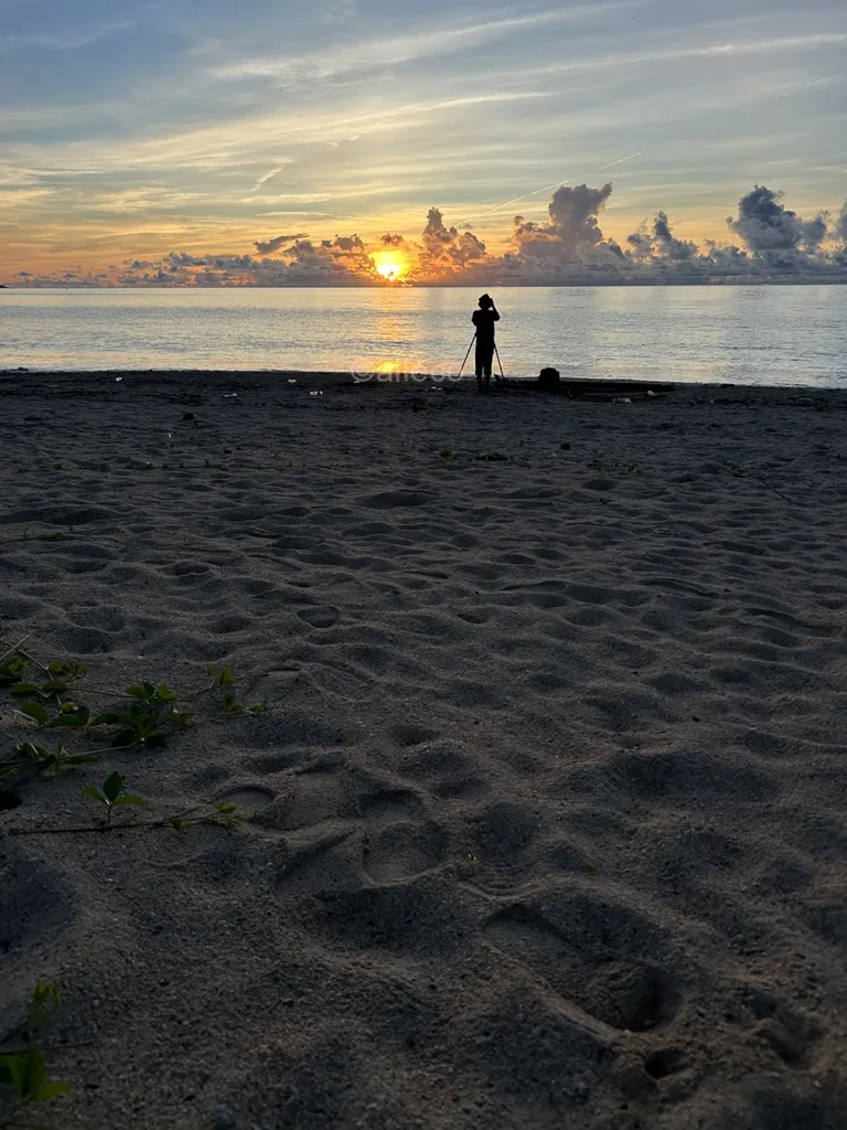 明石海岸で朝日を眺める時間 朝日に照らされた明石海岸で日の出を撮影する人のシルエット